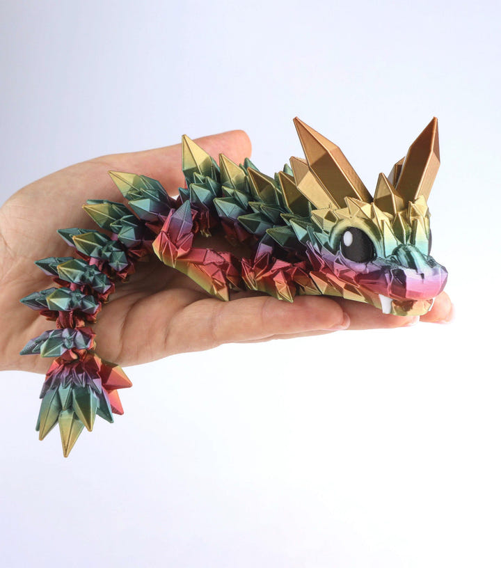 Colorful dragon-shaped toy held in a hand against a white background