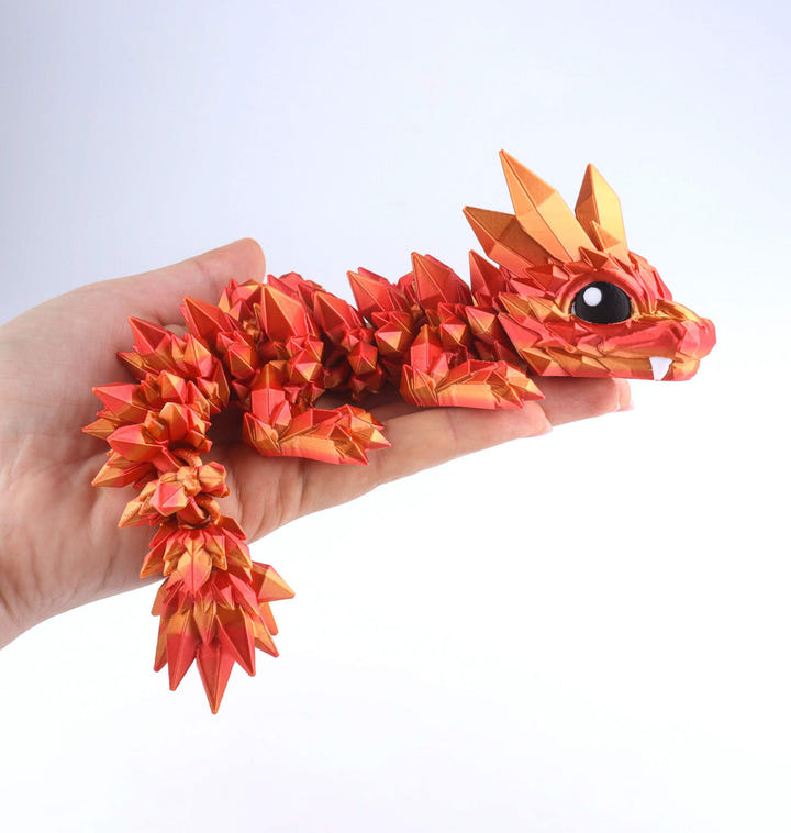 Origami dragon held in a hand against a white background