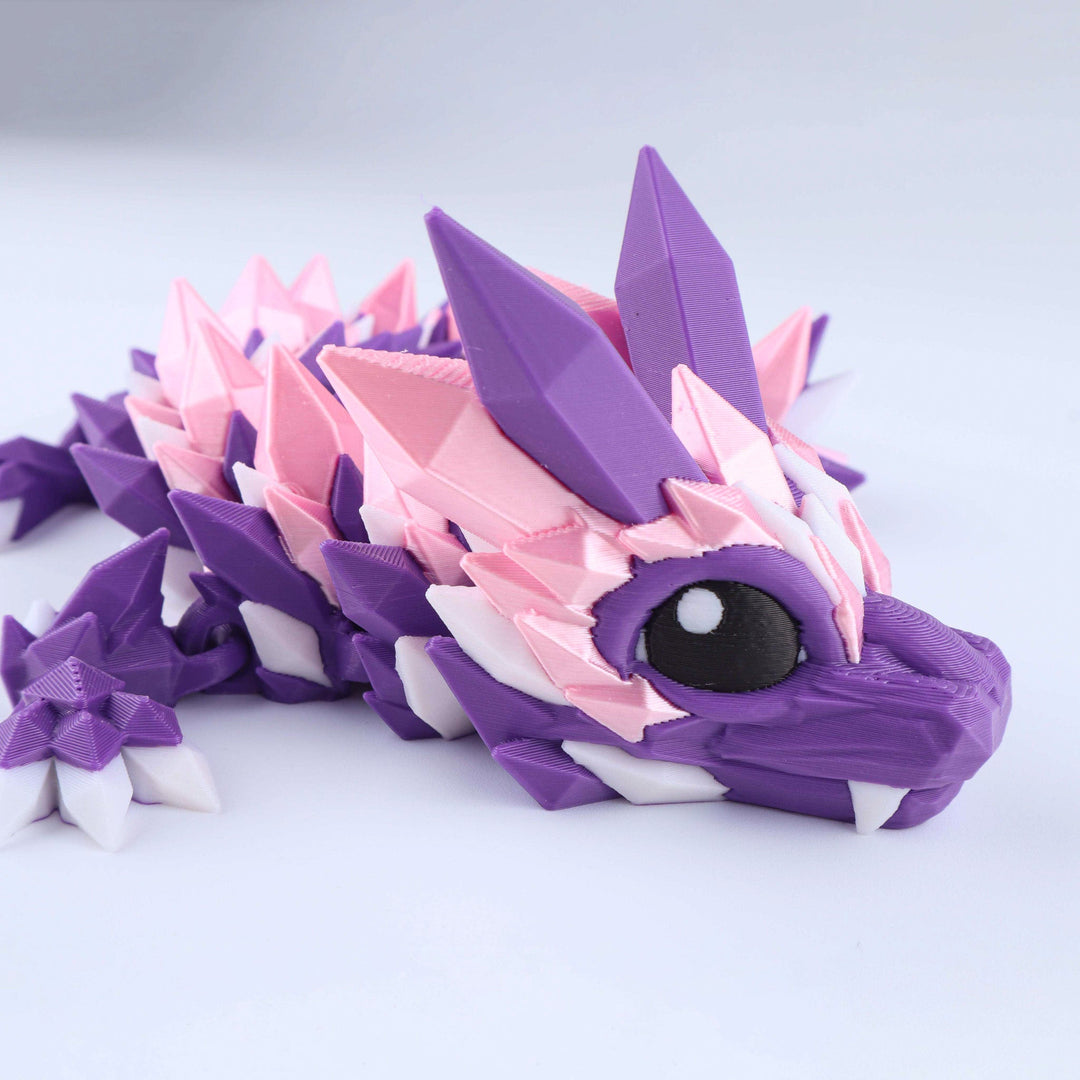 A 3D-printed articulated dragon toy in shades of purple, pink, and white, shown in a close-up side profile on a light gray background.