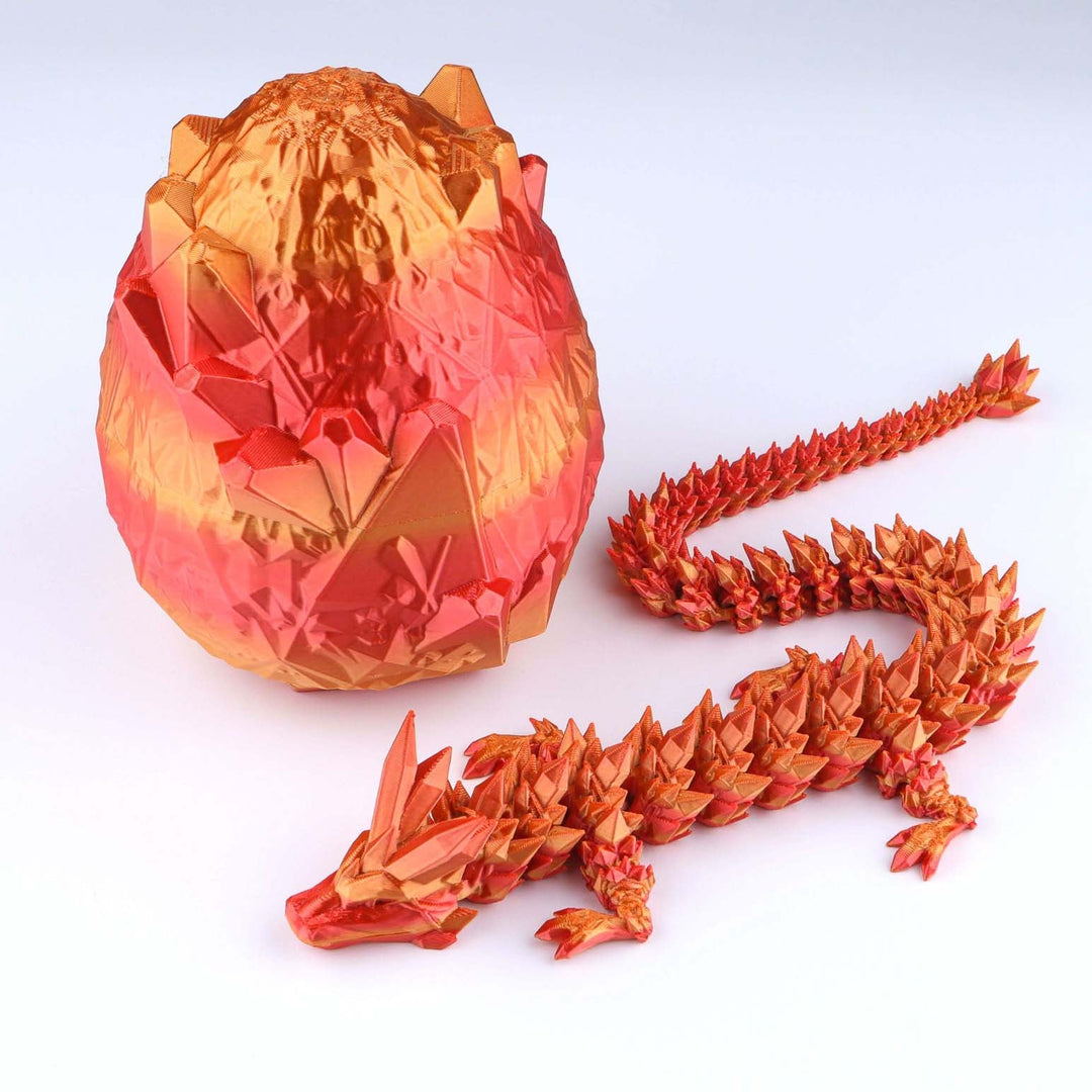 A 3D-printed articulated dragon toy and its matching faceted egg, displayed on a clean white background. The dragon is printed in a metallic orange and red gradient, and the egg features a similar orange-to-red gradient pattern.