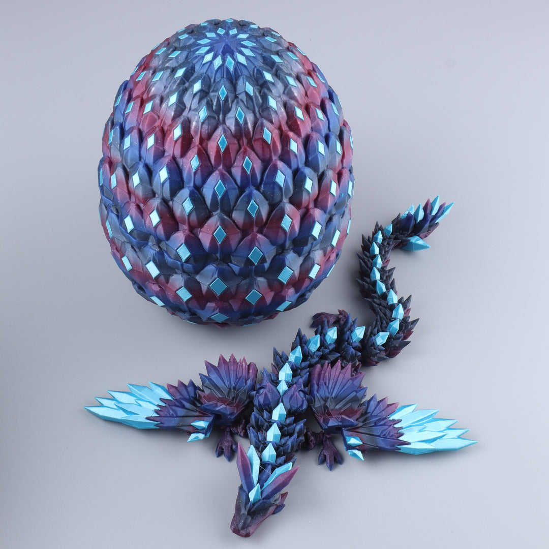 A fantasy dragon figurine and its matching egg, both featuring a faceted, geometric scale pattern in iridescent blue, purple, and pink tones, displayed on a neutral gray background.