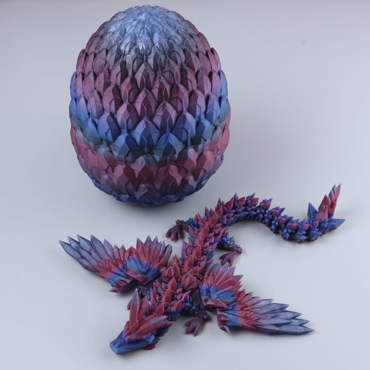 A 3D-printed articulated fantasy dragon figurine shown next to its matching scaled egg on a light gray background.
