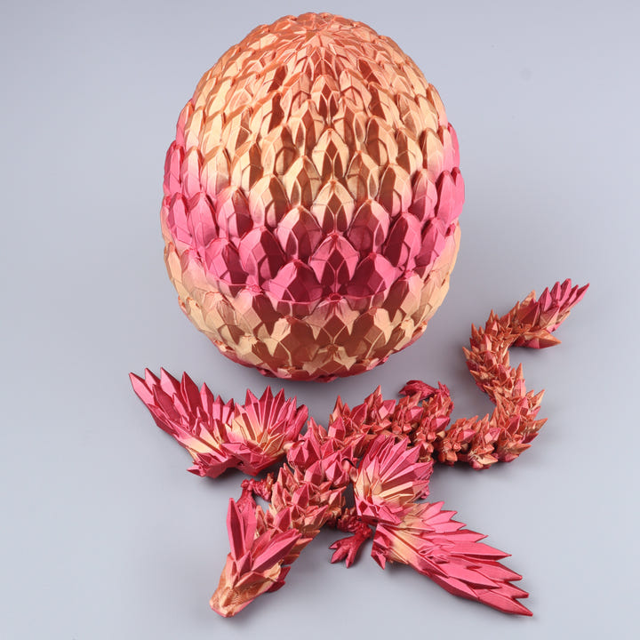 A metallic dragon figurine shown disassembled with its large segmented egg-shaped shell and several body pieces arranged in front on a light gray background.