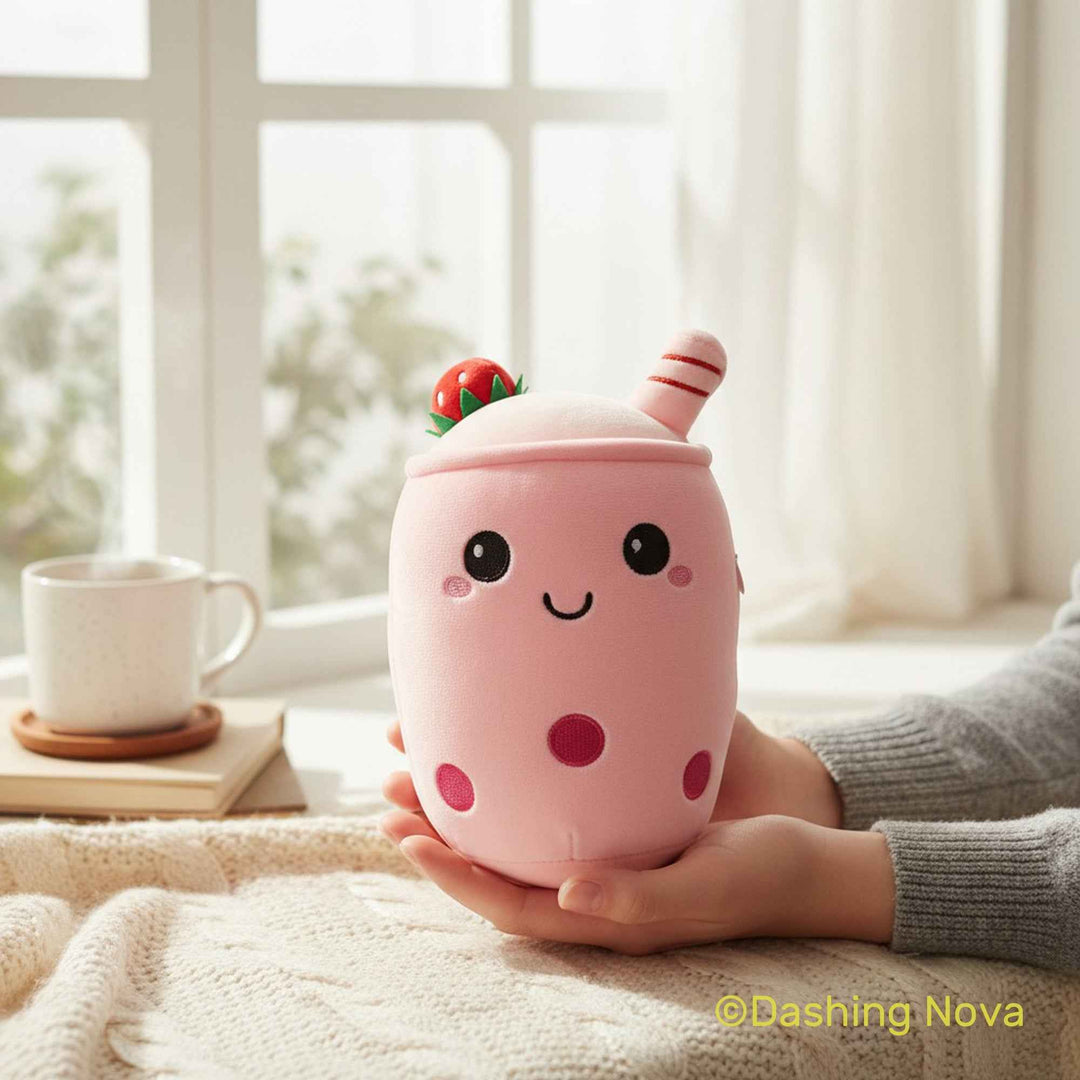 Person holding a pink plush toy resembling a milkshake with a straw and cherry on top, in a cozy indoor setting.